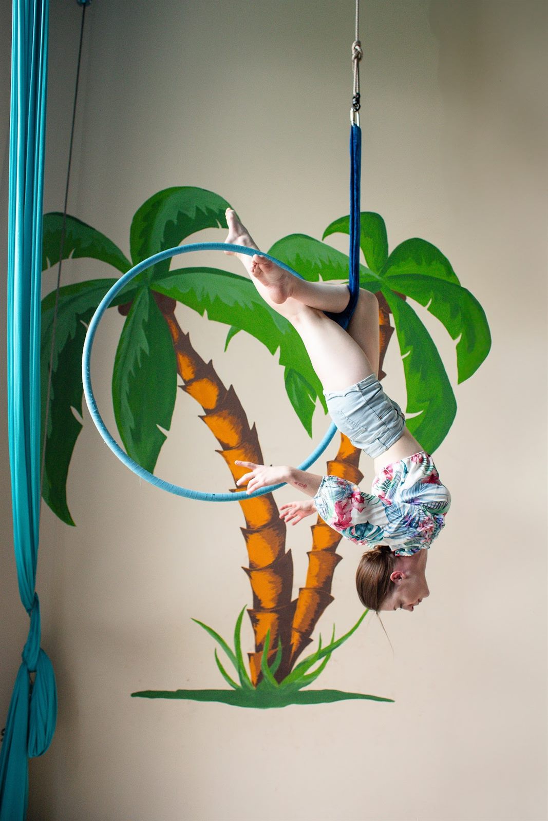 Ćwiczenie na kole przy malowidle z palmami w sali AerialParadise